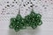 Earrings from beads handmade hang on the stand. Needlework at home. Bead jewelery. Green colour. On a white background.