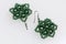 Earrings from beads handmade. Needlework at home. Bead jewelery. Green colour. On a white background.