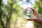 Earth crystal glass globe ball in human hand, environment day concept. Sustainable development of natural resources and the