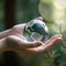 Earth crystal glass globe ball and maple leaf in human hand on grass