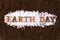 Earth day inscription with text made of wood cutout words on brown natural soil background