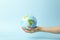 Earth globe in hands on a clean blue background. The concept of protecting nature, ecology and global peace