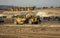 Earth moving equipment at a construction grading site with other tractors lined up in the background