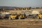 Earth moving equipment at a construction grading site with other tractors lined up in the background