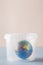 Earth in plastic disposable box on blue and pink background