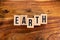 ` EARTH ` text made of wooden cube on  wooden background