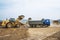 Earthworks on a summer day in mountainous areas. Wheel loaders load soil into the bodies of dump trucks.