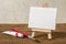 An easel with a blank canvas, paint and brush