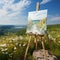 easel with canvas, a painting of a field in a field of wildflowers.