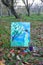 Easel with paints and painting on canvas in autumn park