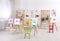 Easels with paintings and chairs for children