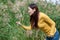 East asian woman bending over picking flowers