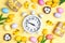 Easter alarm clock with colorful eggs and tulips on yellow background