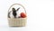 Easter animal and decoration concept. Little cute rabbit bunny black and white sitting in basket with color eggs over isolated