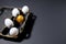 Easter attributes - four white eggs and one golden egg lie in a black tray on a black background. art deco black color horizontal
