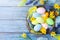 Easter background with colorful eggs in nest, feather and spring flowers top view. Holiday card or banner