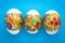 Easter background. Colorful paschal eggs with ornament on blue backdrop. Festive event. Spring season. Gift card, concept of
