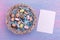 Easter background with colorful quail eggs, feathers in a wicker basket and an empty paper near it, top view. Copy space