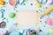 Easter baking background with paper card, rolling pin, whisk, decorative eggs, cookie cutters, candy and colorful confetti