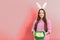 Easter banner, Happy girl in the bunny ears with a basket of decorated eggs smiling on a pink background in studio with copy space