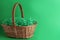 Easter basket with bright paper filler on green background, space for text