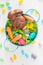 Easter basket with chocolate rabbit, candy eggs, and mini carrots on white background with jellybeans