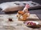 Easter basket with a rabbit figurine with multicolored chocolate eggs on a light tray standing