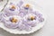 Easter bird nest meringue cookies - lilac mini Pavlova desserts with pastel candy eggs in nest shape for Easter holiday party.