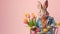 Easter bunny in a blue jacket carrying shopping cart with Easter eggs and tulips , pink background with copy space