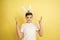 Easter bunny boy with bright emotions on yellow studio background