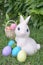 Easter bunny and Easter eggs, rabbit statues and colorful pastel eggs at the backyard garden. Soft focus on the eyes of Easter bun