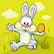 Easter bunny sitting on green grass holding egg