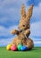Easter bunny from straw with colored eggs on grassland