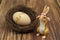 Easter bunny with a wicker nest and a wooden egg with a golden inscription