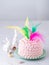 Easter cake decorated with feathers of different colors and colorful eggs on festive Easter gray background with copy space.