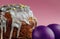 Easter cake with white flowing icing and colored confetti with purple colored eggs close-up on a pink background , a sponge cake.