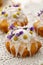 Easter cakes covered with icing decorated with spring and edible flowers on lace white tablecloth, close-up.