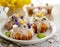Easter cakes covered with icing decorated with spring and edible flowers and marzipan eggs on an Easter table.