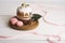 Easter cakes and eggs with light, modern design on a white wooden back with pink ribbon. Easter food. Easter symbol