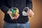 Easter celebrating. Female holding glass vase with colourful quail eggs in hands on beige studio background, close up