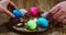 Easter celebrating. Hands putting colourful painted eggs on plate, close up video. Festive preparations
