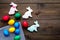 Easter celebration with colorful eggs and gingerbread in shape of easter bunny and carrot. Wooden background top view