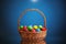 Easter color eggs in festive gift basket, blue background