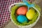 Easter colored eggs in a basket on a canvas napkin and checkered tablecloth