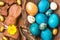 Easter colored eggs, chocolate bunny and sweets on rustic wooden background.