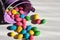 Easter colorful jelly beans candies spilling from the decorative bucket onto a white table. Top view. Copy space