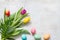 Easter colorful spring tulips with palm and eggs decoration on white wooden natural background