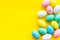 Easter composition. Decorated pastel Easter eggs on yellow background copy space border