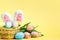 Easter composition. Eggs in a basket tulips rabbit ears on a yellow background