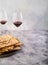 Easter composition on a gray marble background. Traditional Jewish bread matzah and two glasses of red wine. Jewish Passover,